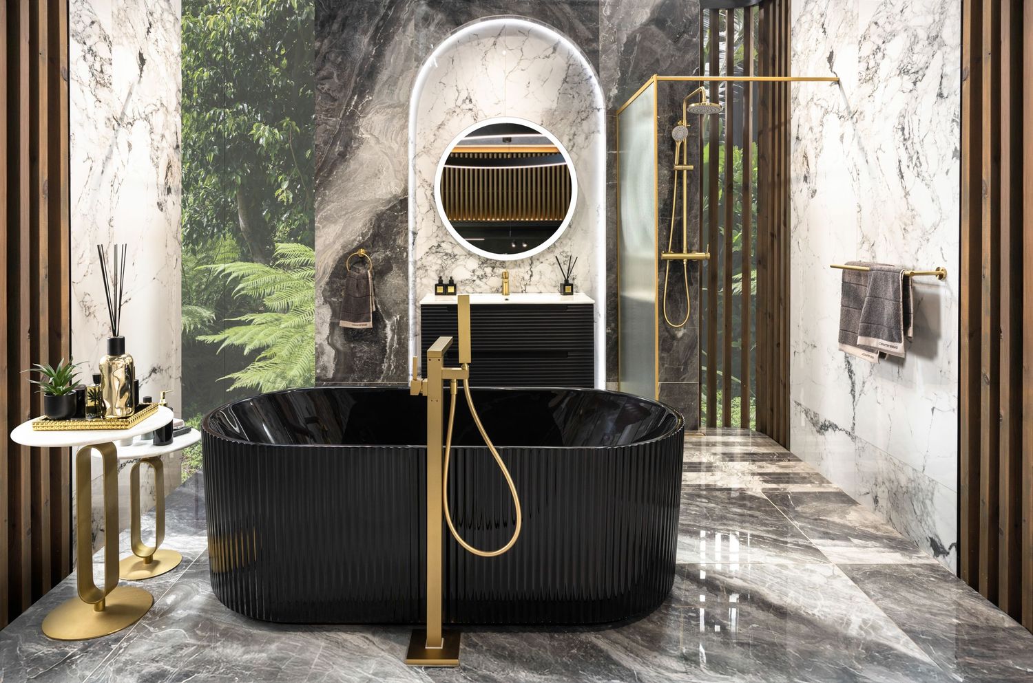 Luxurious modern bathroom with black freestanding tub, gold fixtures, and natural light streaming through large windows.