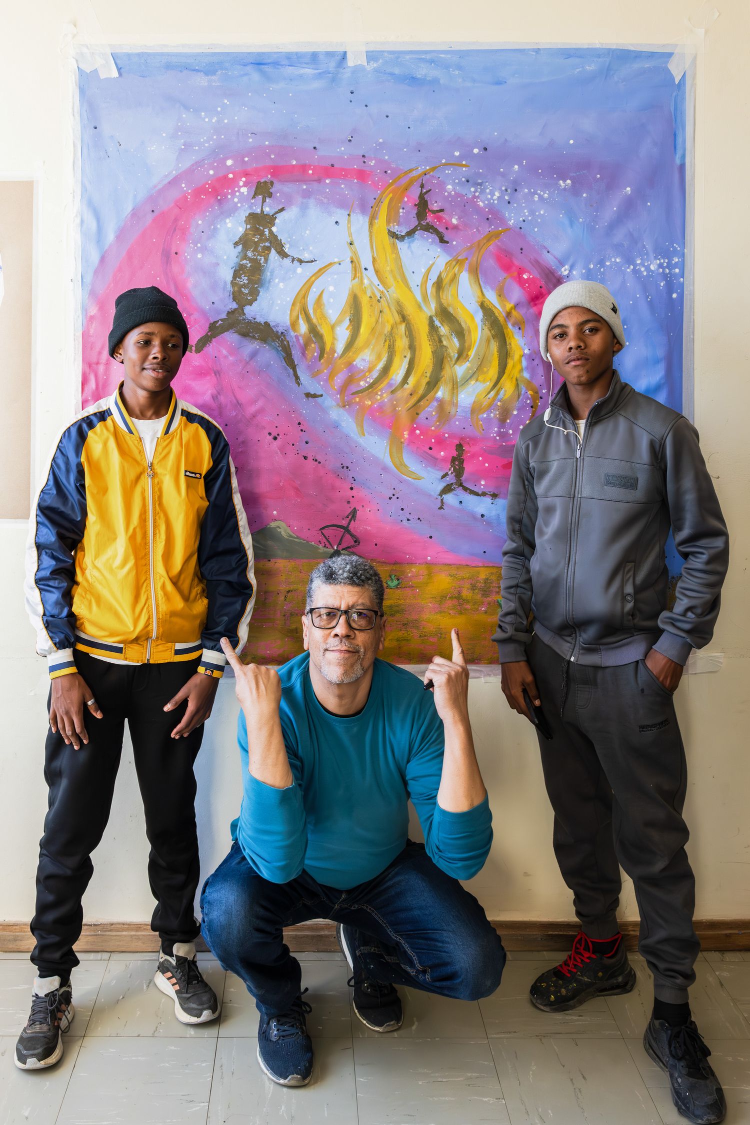 Group posing in front of vibrant cosmic-themed artwork with pink and purple colors.
