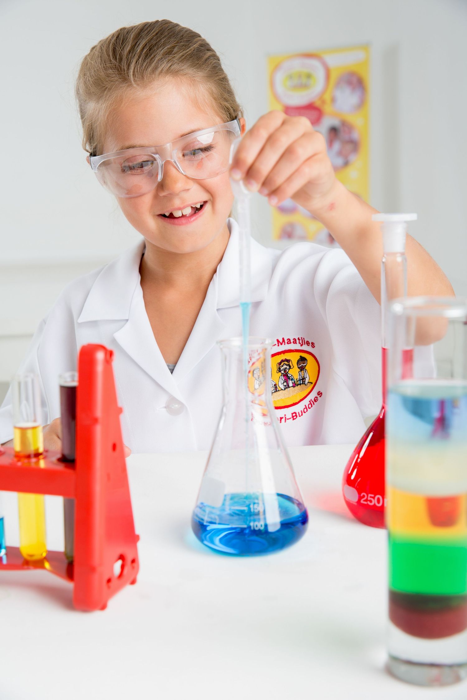 Young scientist in a white lab coat conducts experiments with colorful liquids in beakers and flasks.