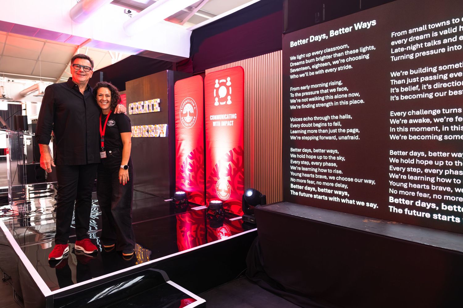 Modern exhibition space with dark walls displaying illuminated text panels and red accent lighting.