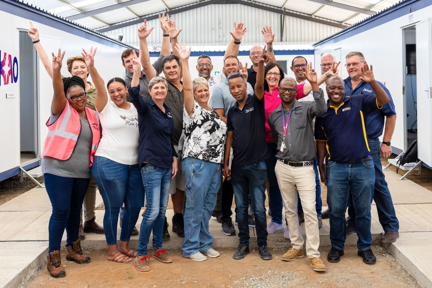 Large group of industrial workers gathered for group photo in warehouse facility.