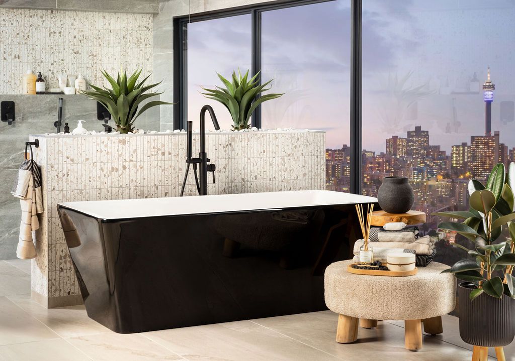 A modern bathroom with a black freestanding tub, city views through large windows, and minimalist decor.
