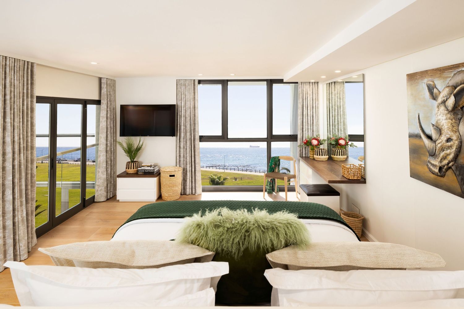 Panoramic view of a modern white living room with floor-to-ceiling windows overlooking a scenic mountain landscape.