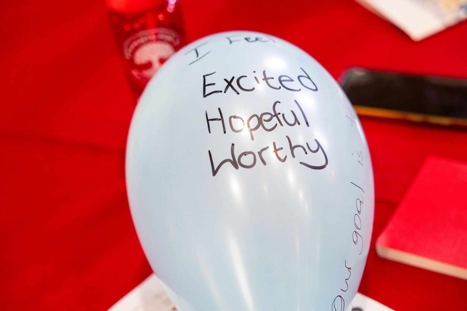 White balloons with handwritten text against a bright red background.