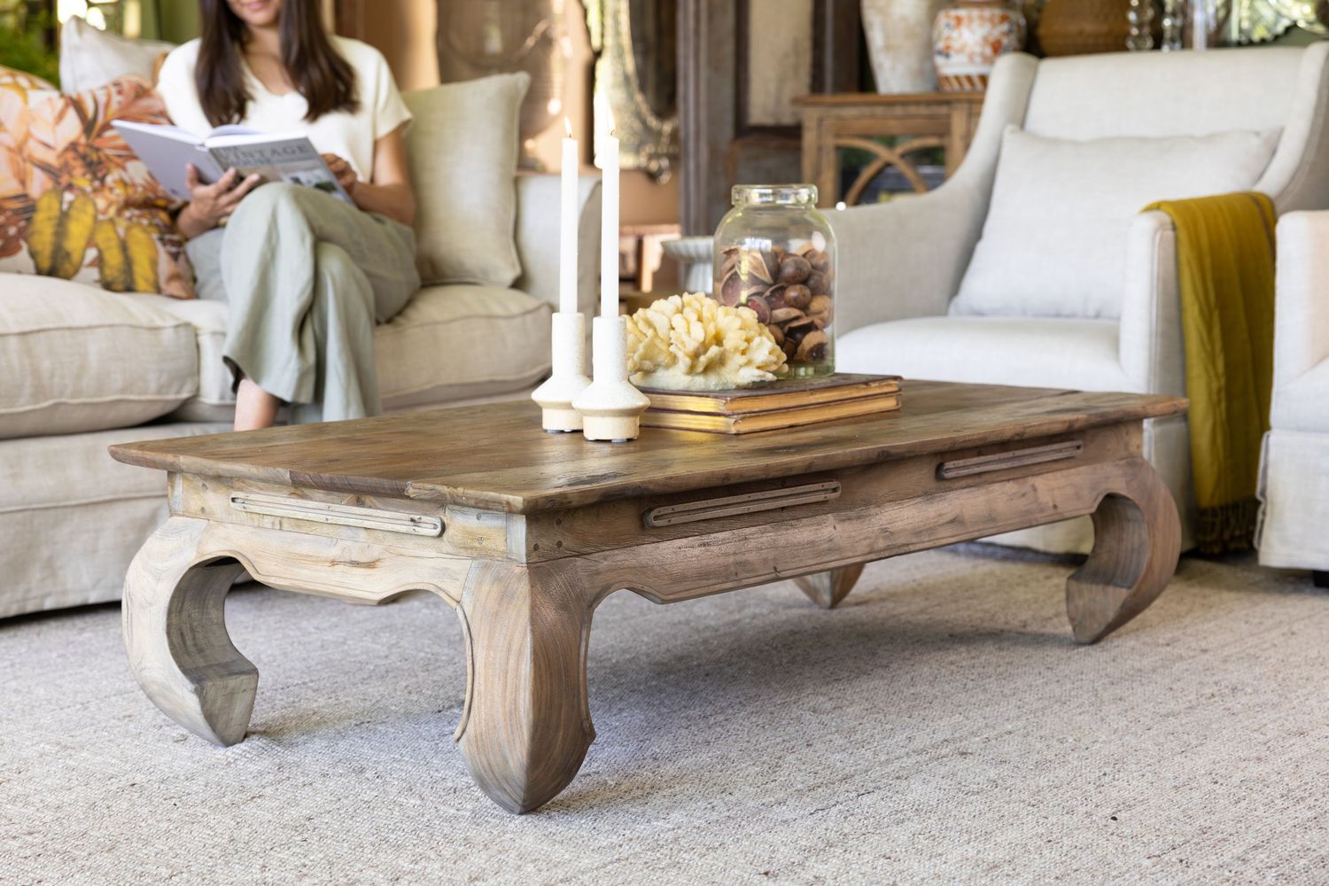 Elegant rustic coffee table with curved legs styled with decor in a contemporary living room setting.