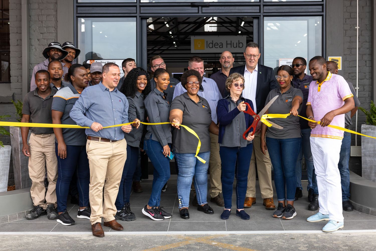 Group photo of staff and visitors gathered outside storefront entrance.
