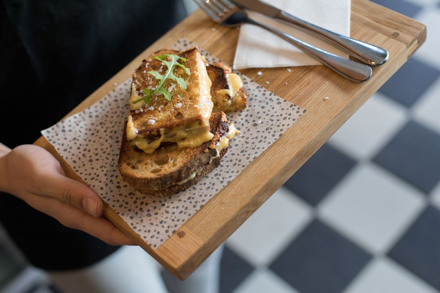 Wooden serving board with freshly plated food in a restaurant setting.