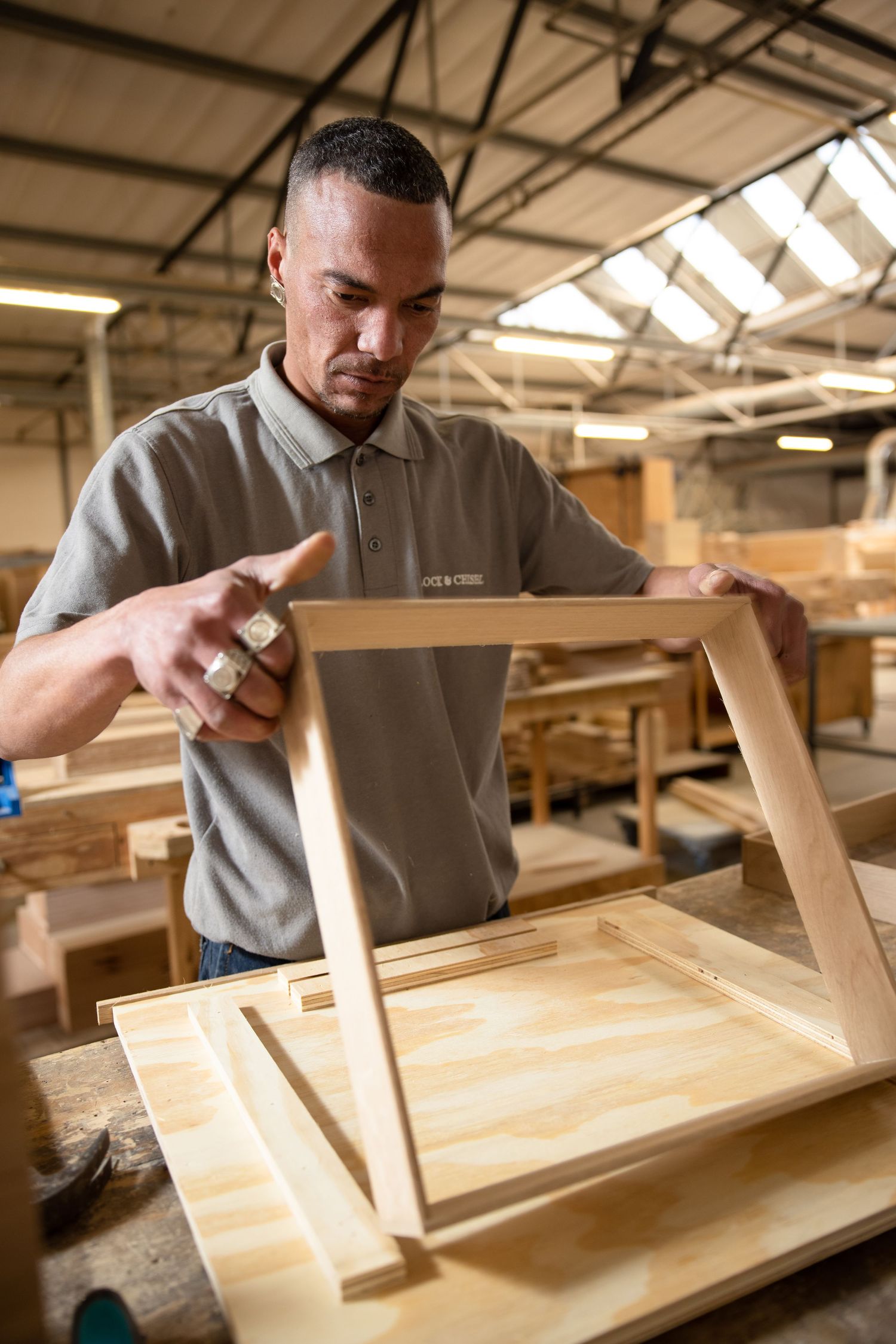 Craftsperson assembling wooden furniture components in workshop.
