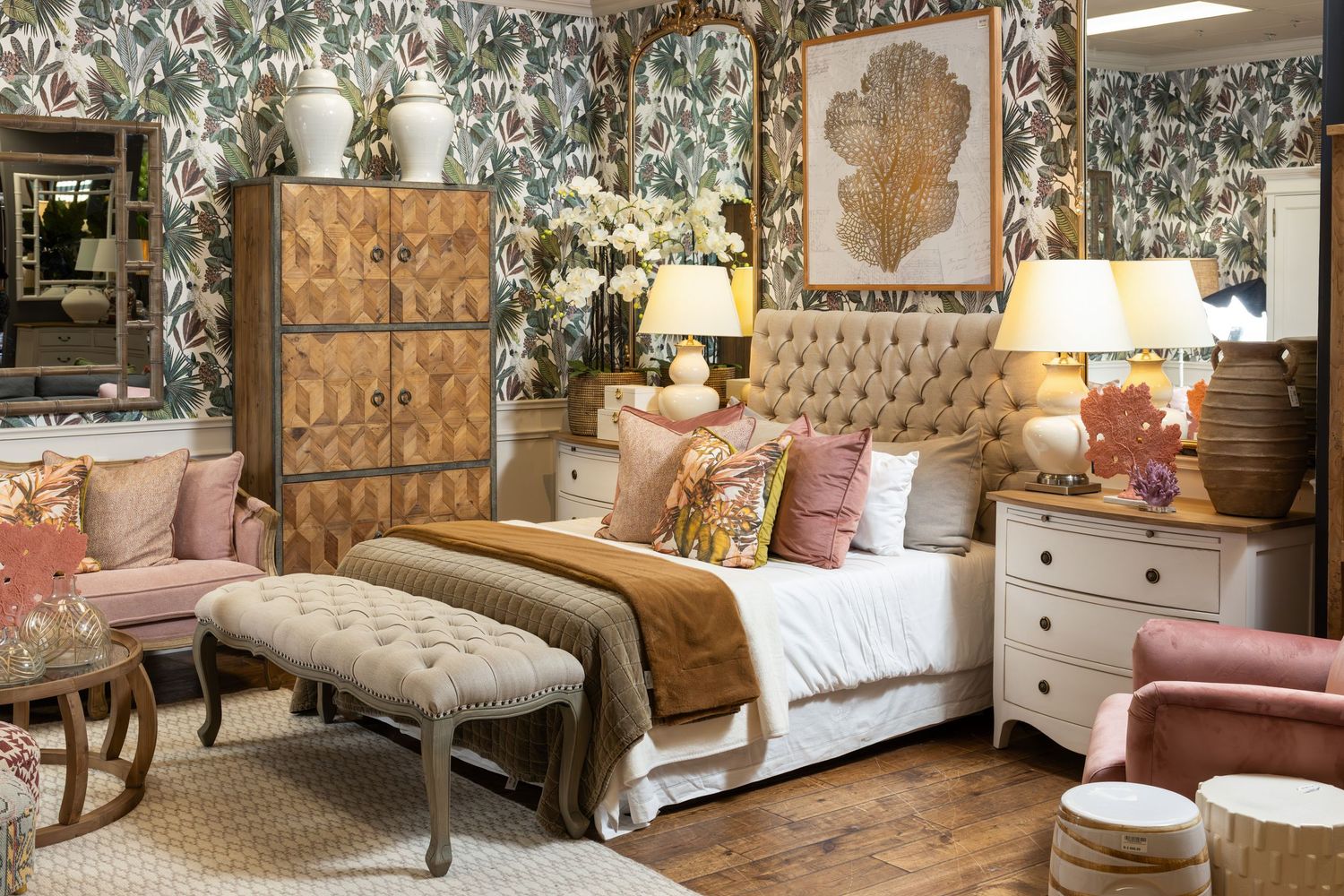 Romantic bedroom with floral wallpaper, tufted headboard, and mix of vintage and modern furnishings.