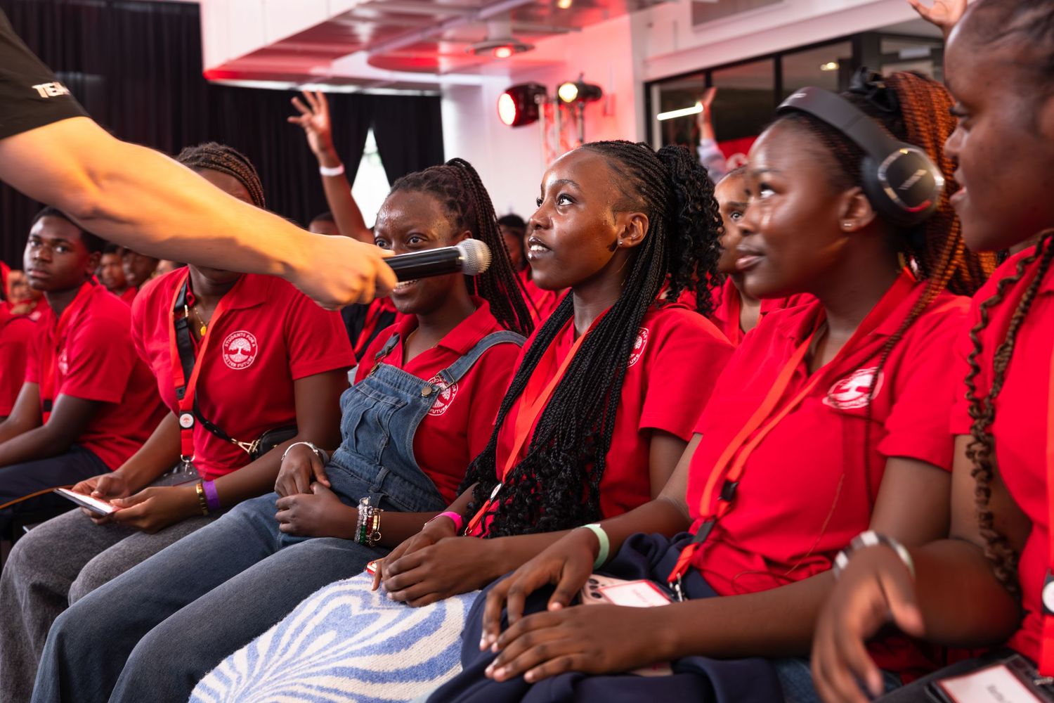 Audience members in red shirts seated and engaged during a professional conference presentation.