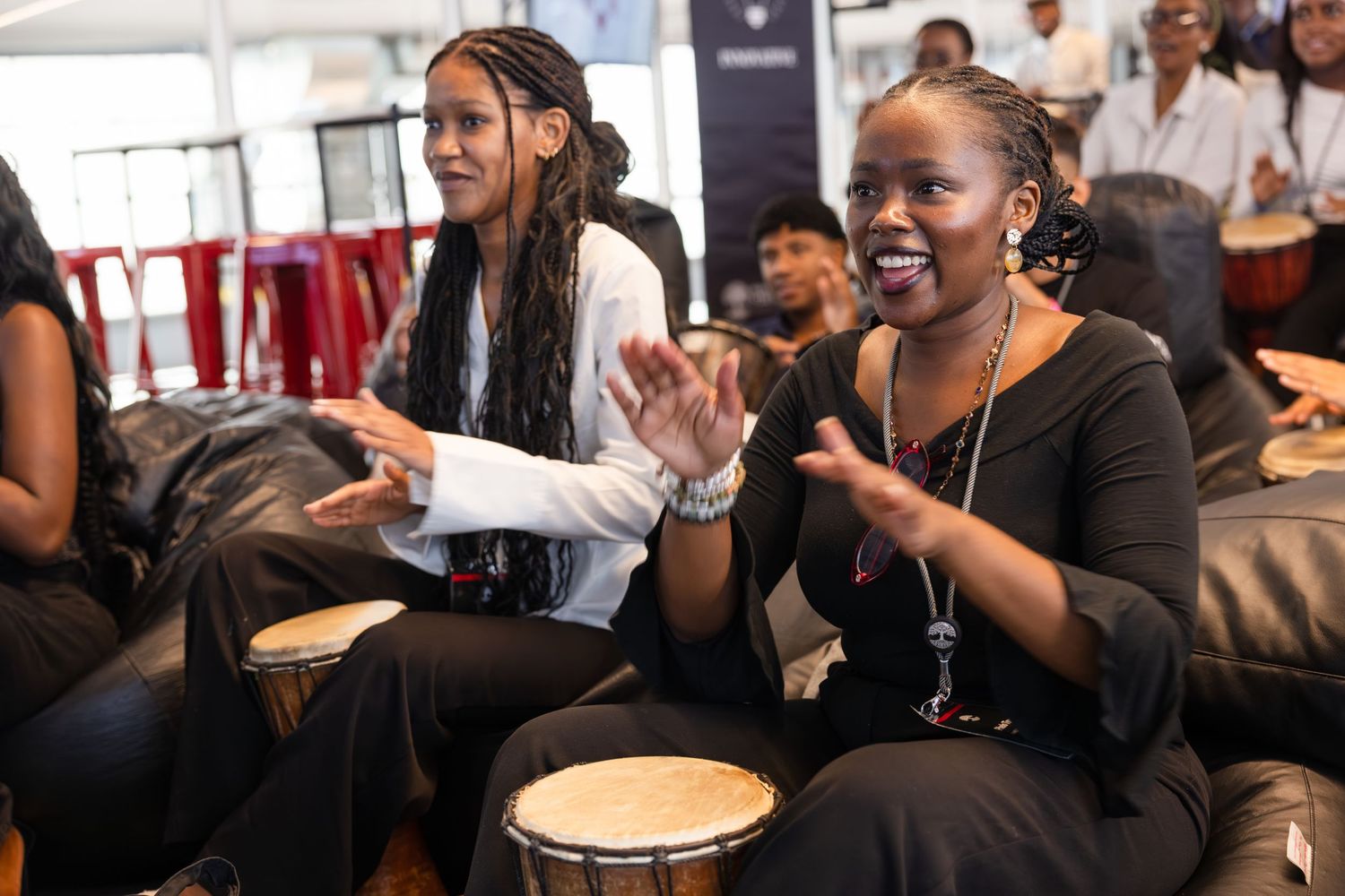 Conference attendees play drums and engage in interactive musical activity during event.