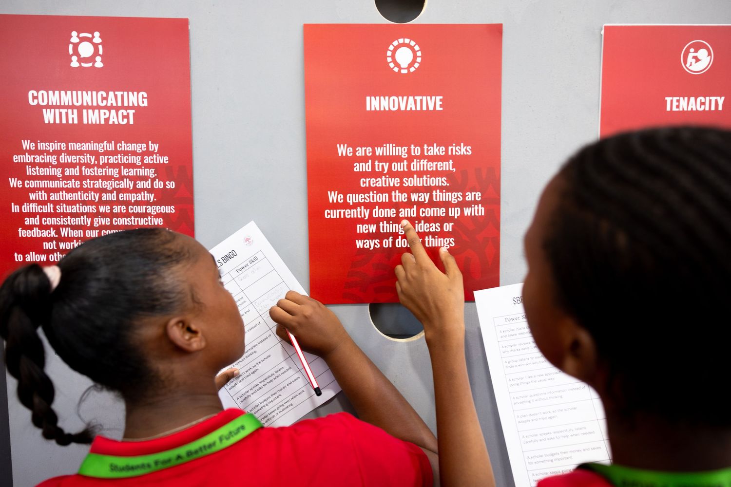 Students interacting with educational wall displays featuring red and white text panels.