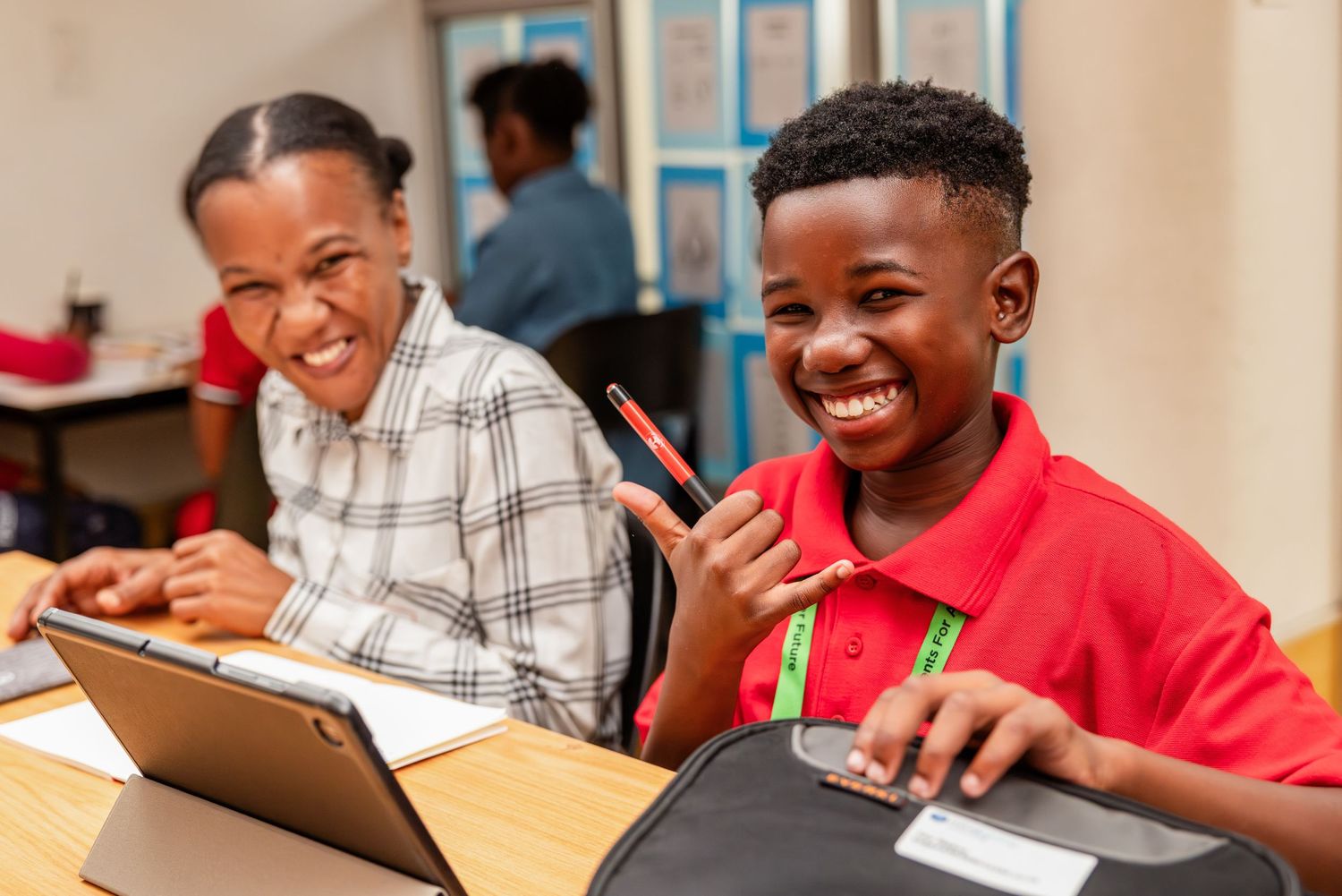 Students share a light moment while working together on digital tablets in classroom.