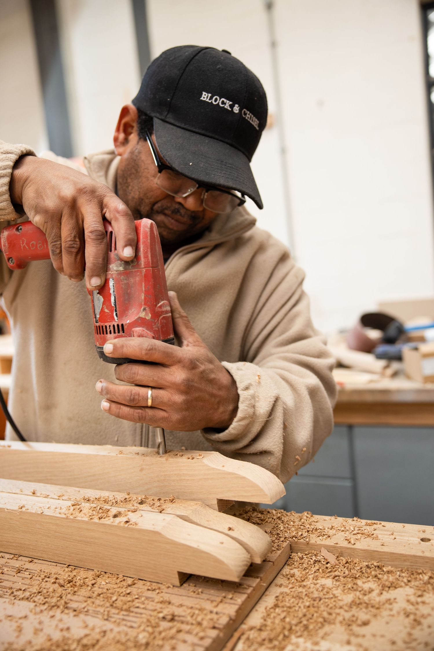 Worker using power sander on wooden surface in workshop environment.