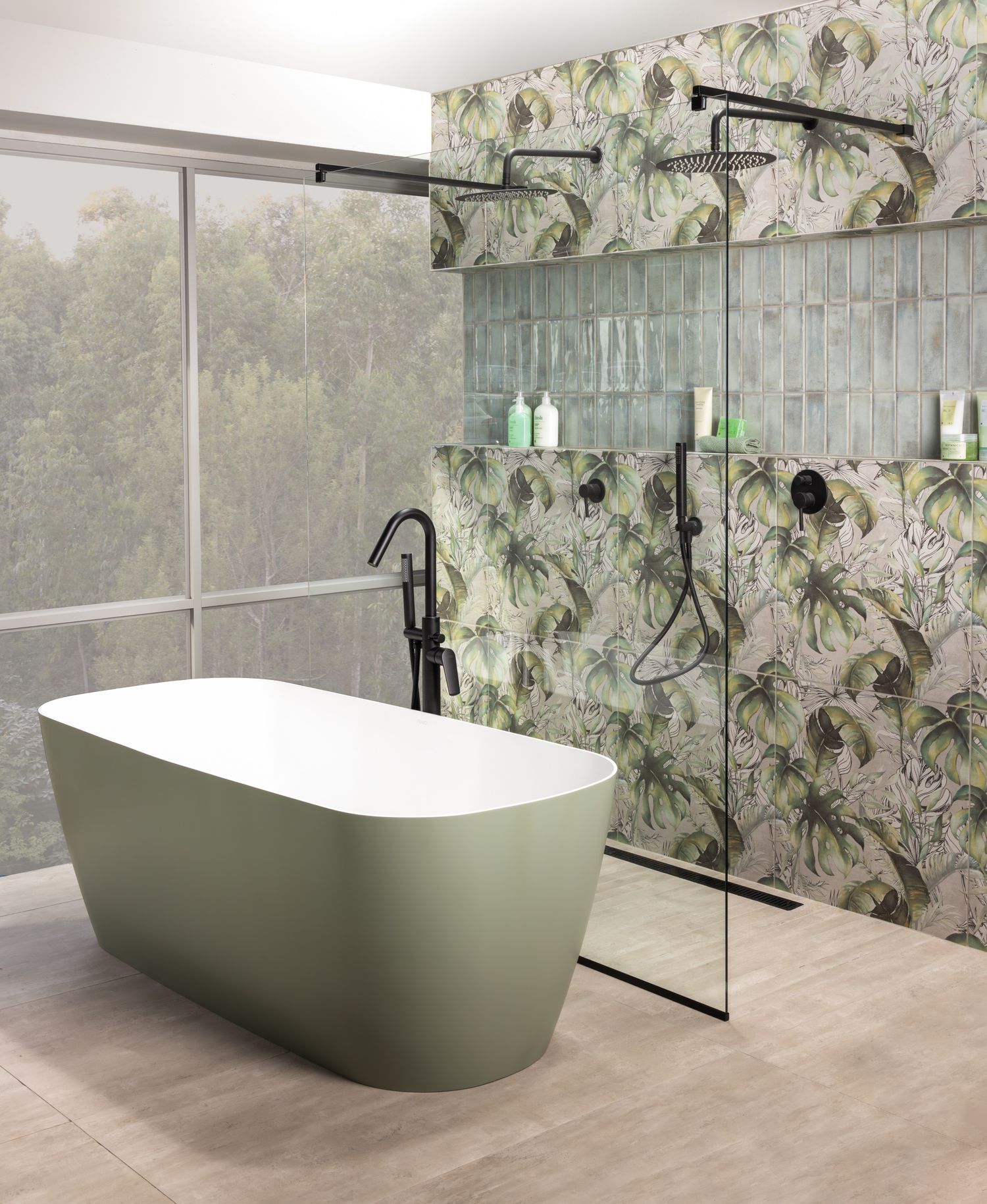 Contemporary bathroom with sage green tub, floral wallpaper, and glass shower partition overlooking forest view.