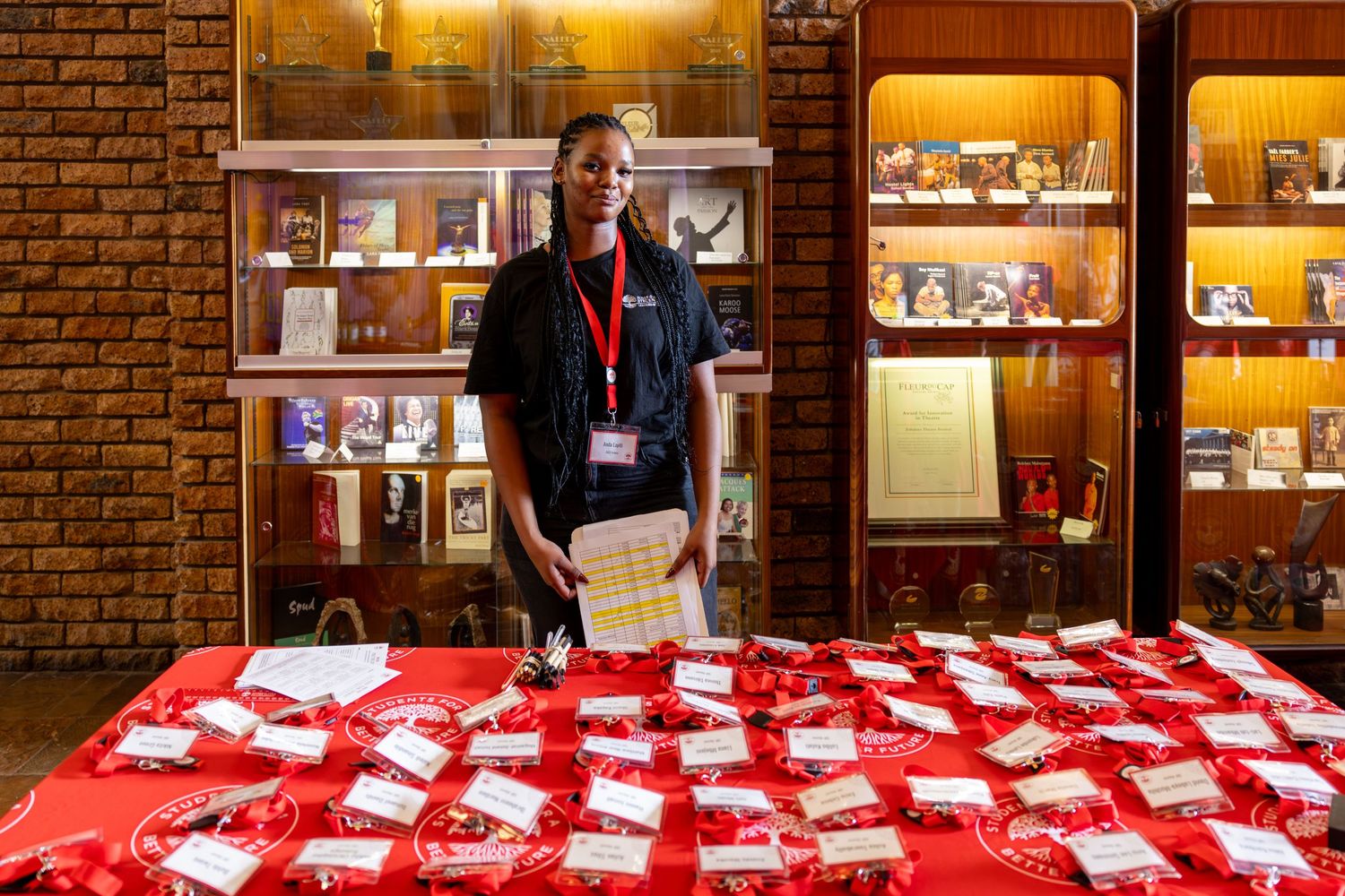 Long registration table with red tablecloth set up against brick wall at an event venue.