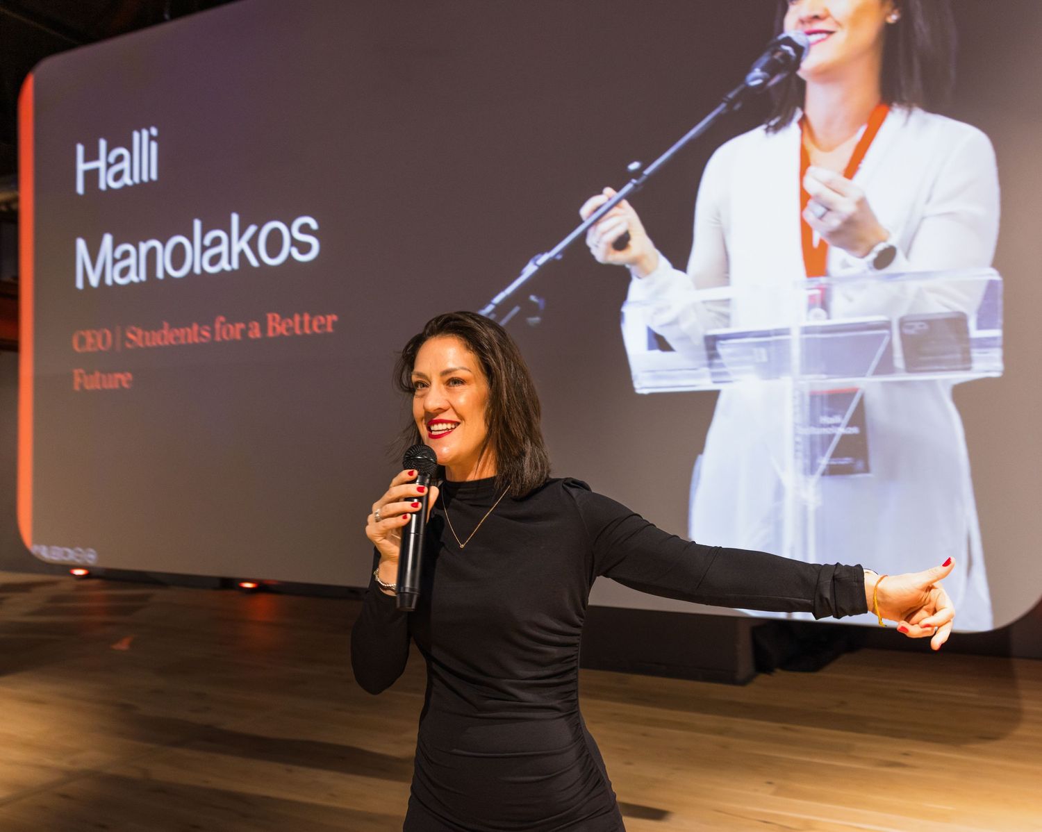 Speakers engage with an audience during a professional presentation in an auditorium with large displays.