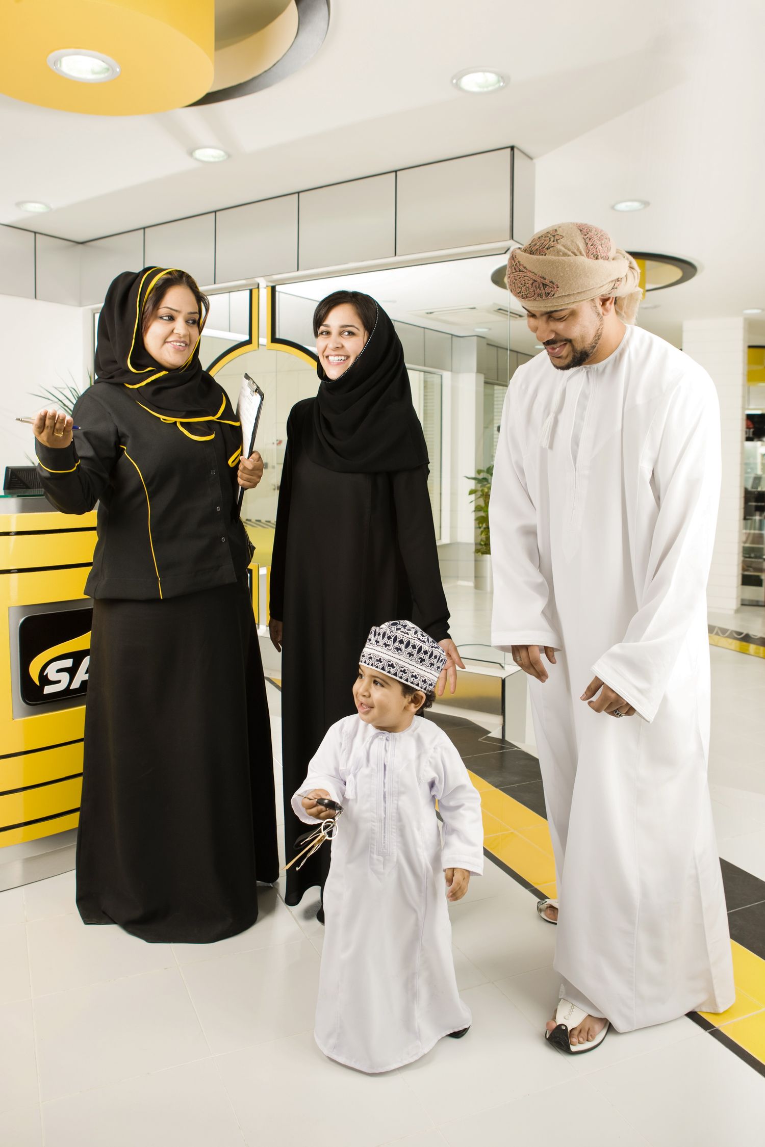 Traditional Gulf family standing together at modern auto service center.