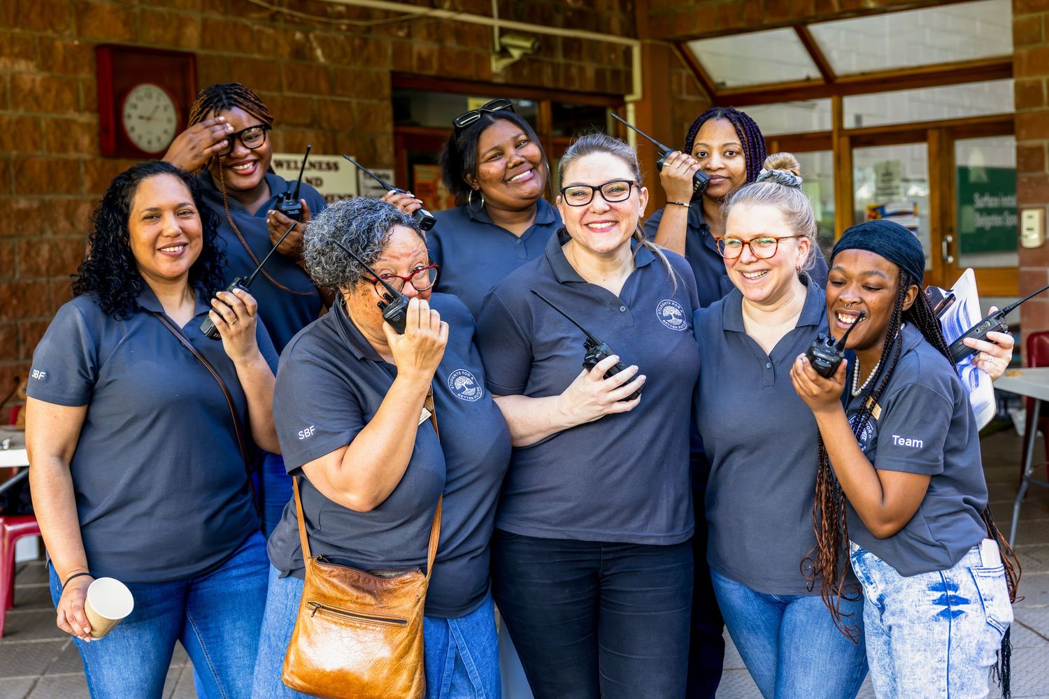 Team of staff members in matching navy uniforms sharing a joyful moment together.
