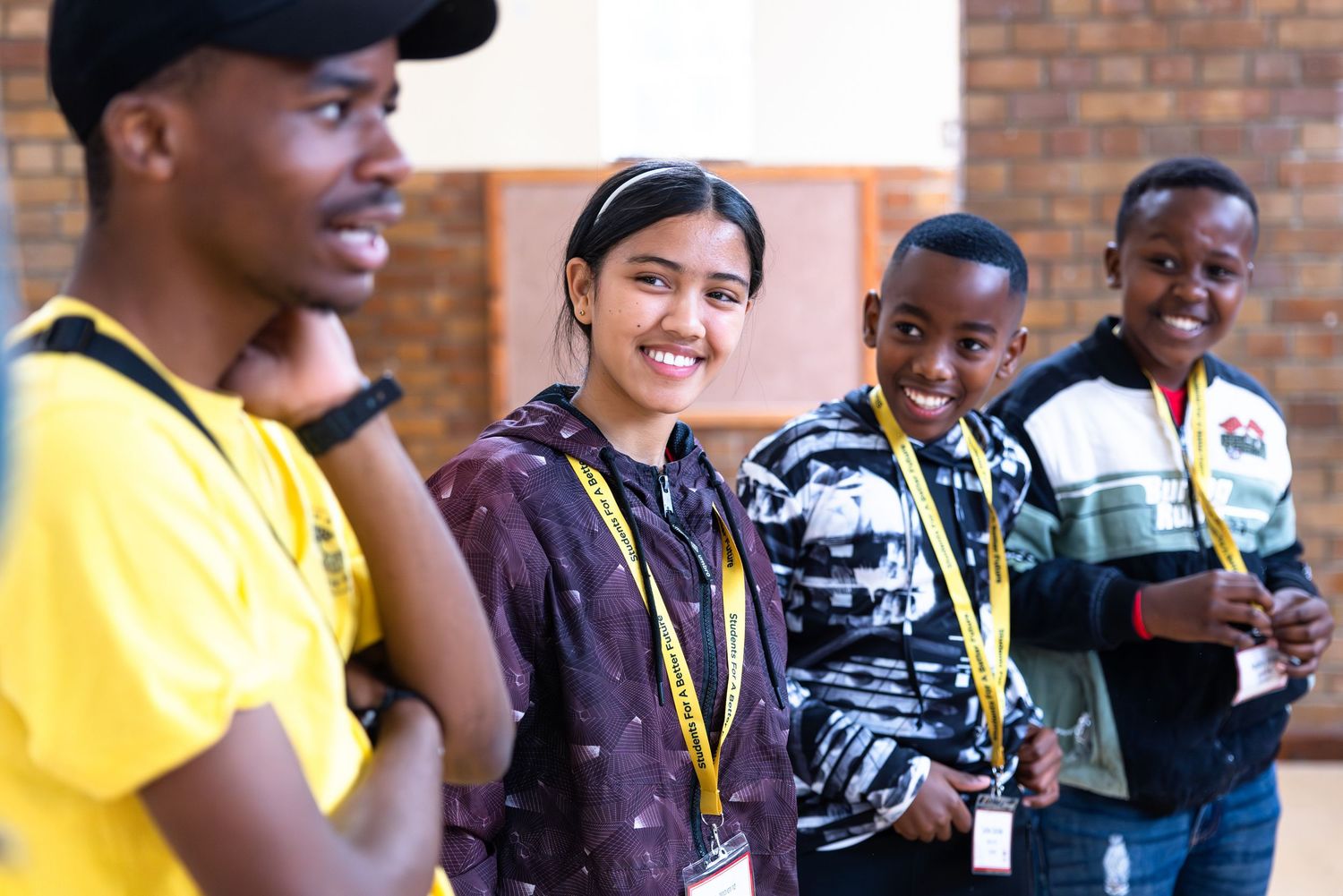 Diverse group of students wearing lanyards smile during educational program.