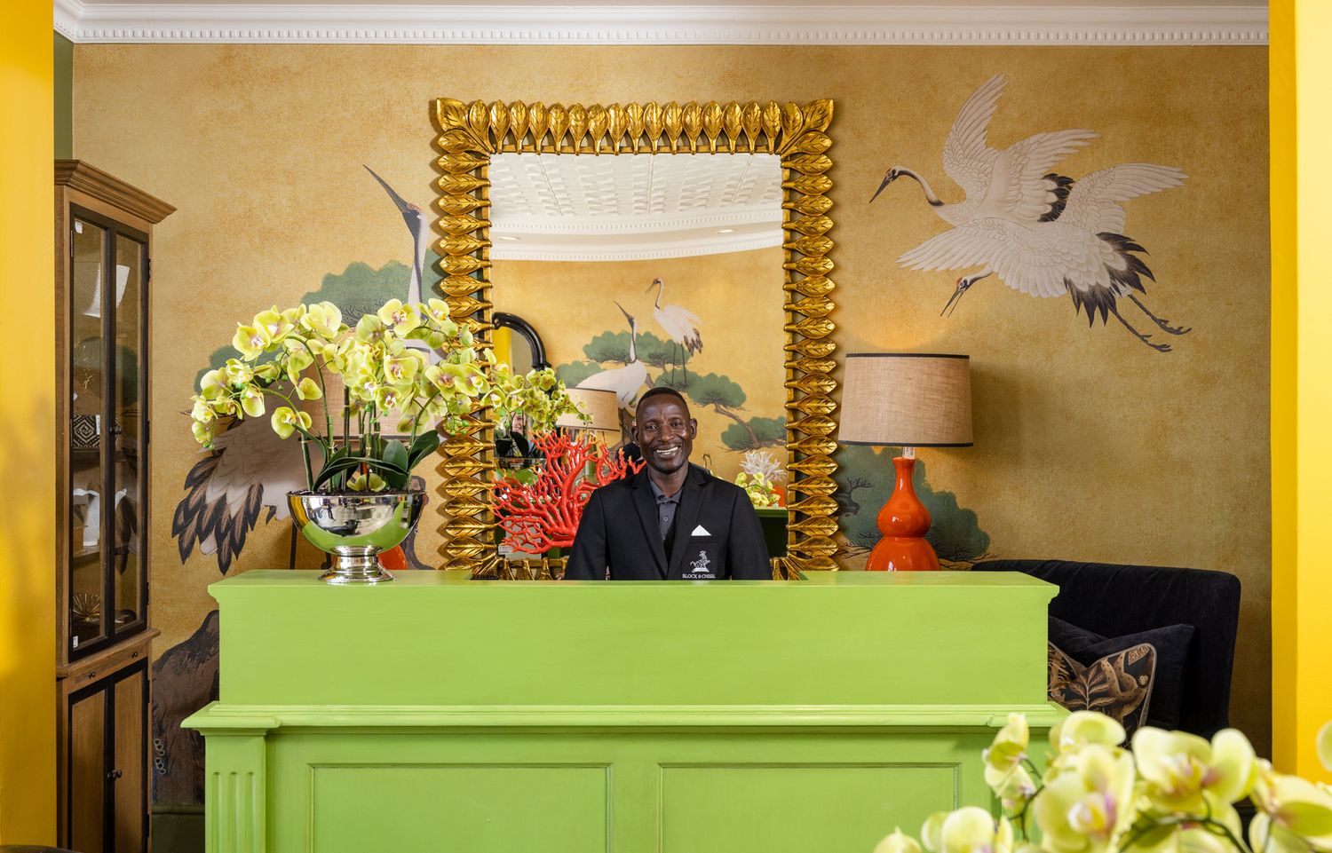 Bright interior with lime green painted piano and gold-framed mirror against mustard yellow wall.