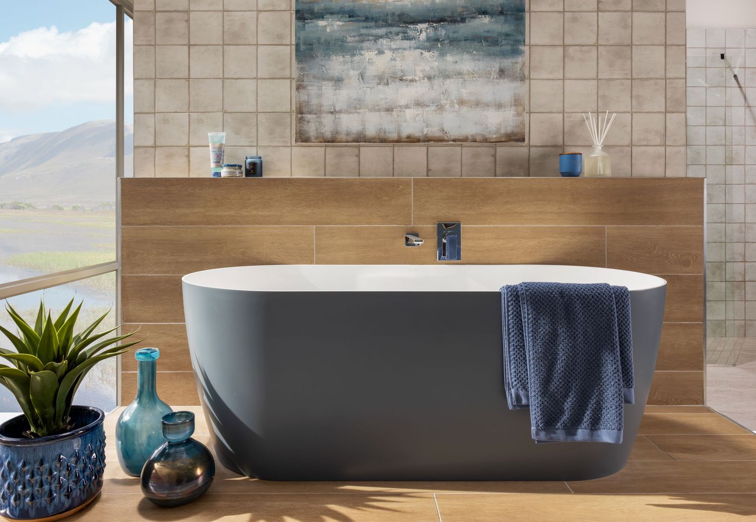 Modern two-tone bathroom with freestanding grey tub, wooden accent wall, and scenic mountain views.
