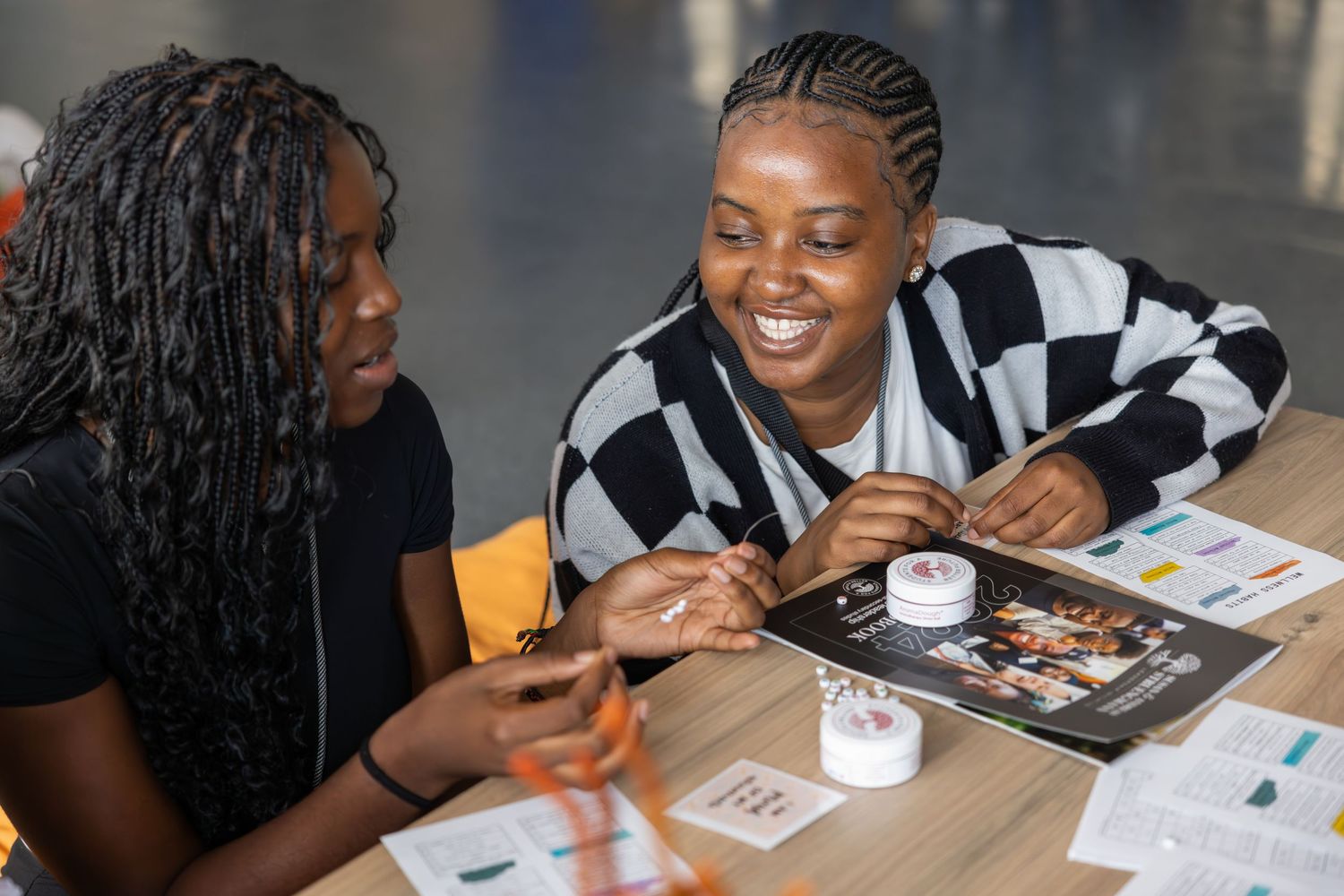 Two students share a laugh while reviewing materials together at a table.