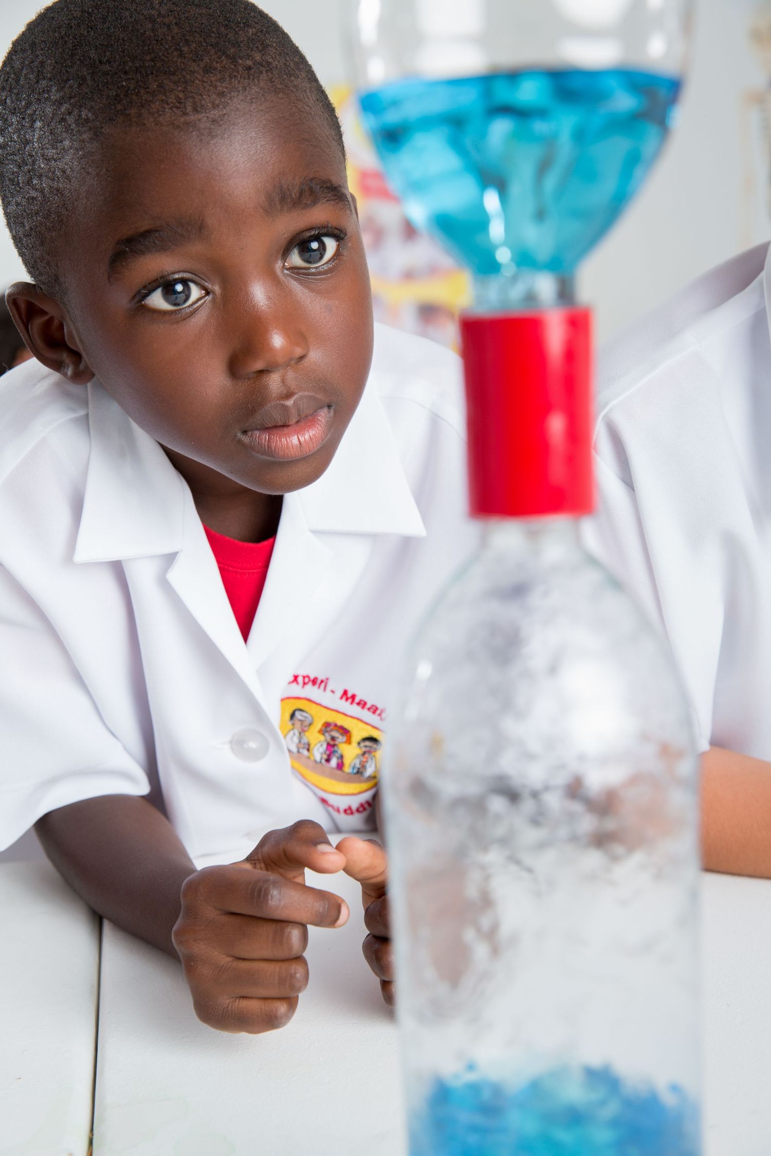 Student observes blue liquid in scientific glassware during chemistry experiment.