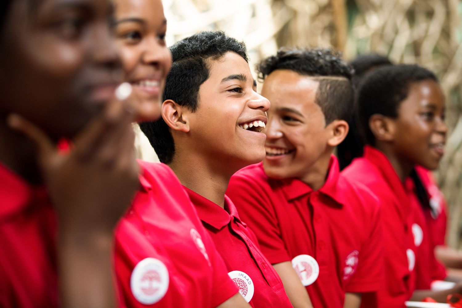 Students wearing matching red shirts smile during an engaging educational program.