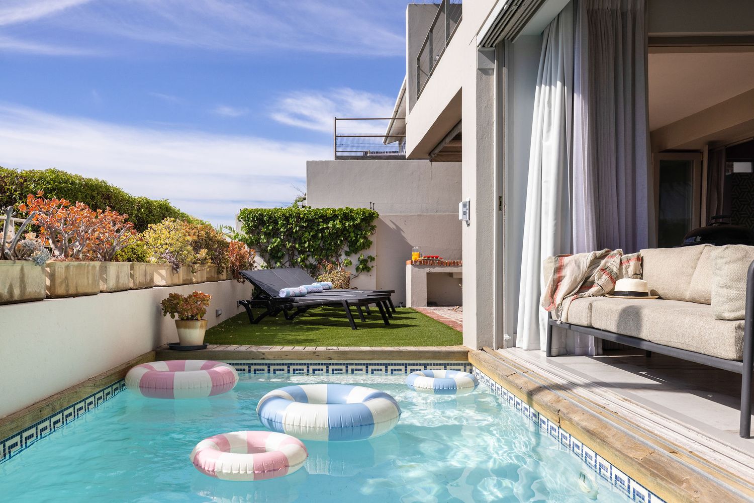 Pink flamingo pool float drifts in a luxurious infinity pool overlooking a scenic coastal landscape.