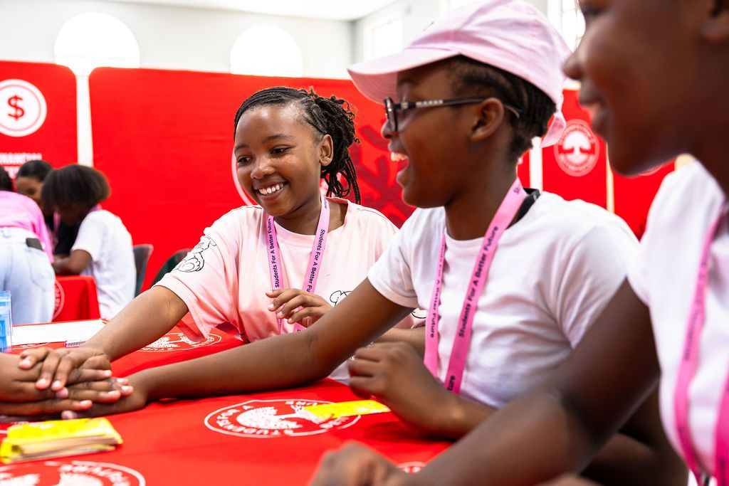 Students participate in a group activity at a table decorated with red tablecloths and pink accents.