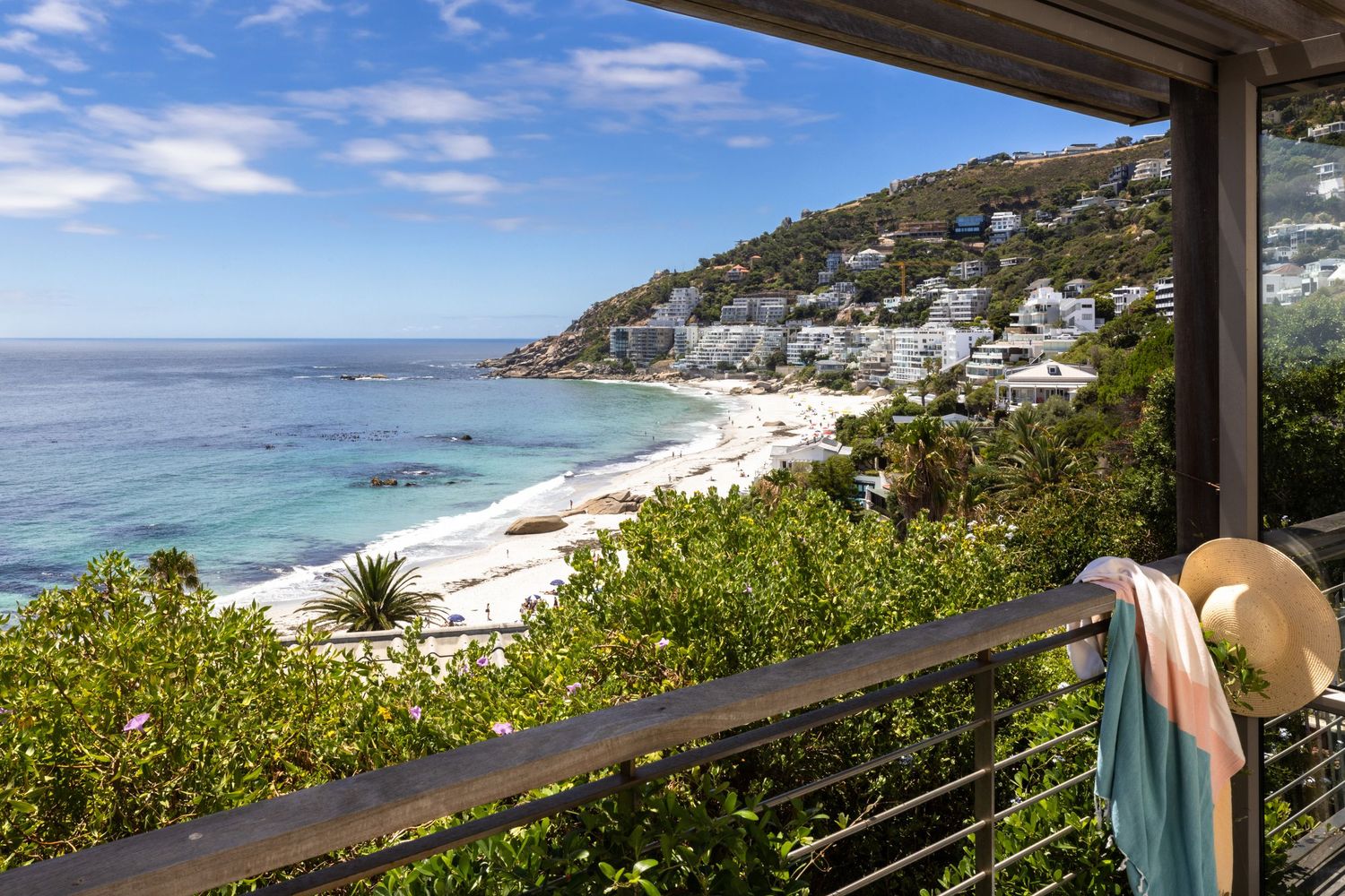 Panoramic coastal view from a luxury beach house deck showing blue ocean waters and mountainous coastline.