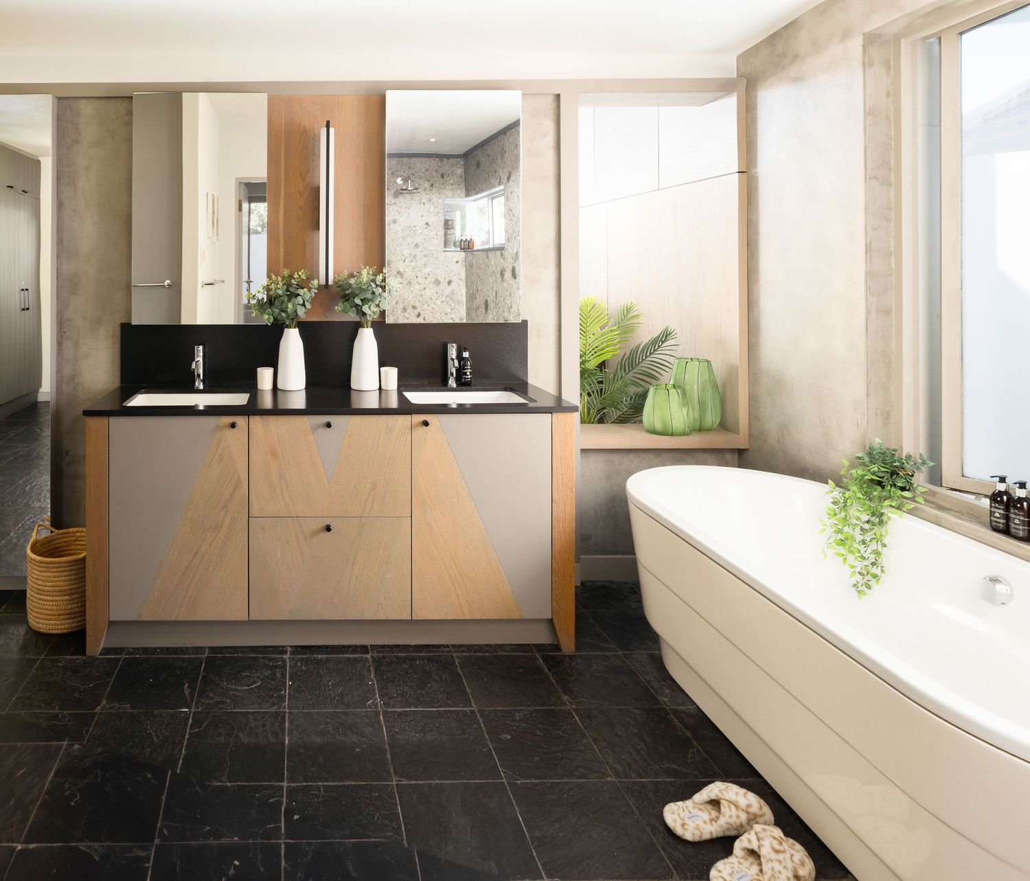 Modern bathroom interior with black slate tile flooring, light wood cabinetry and white walls creating a sleek aesthetic.