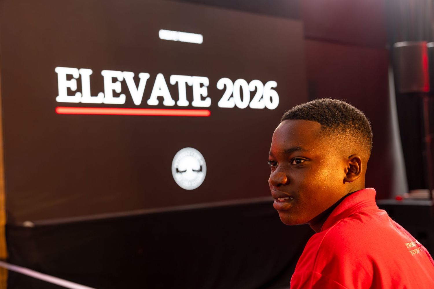 Conference stage setup with 'ELEVATE 2025' signage visible in background.