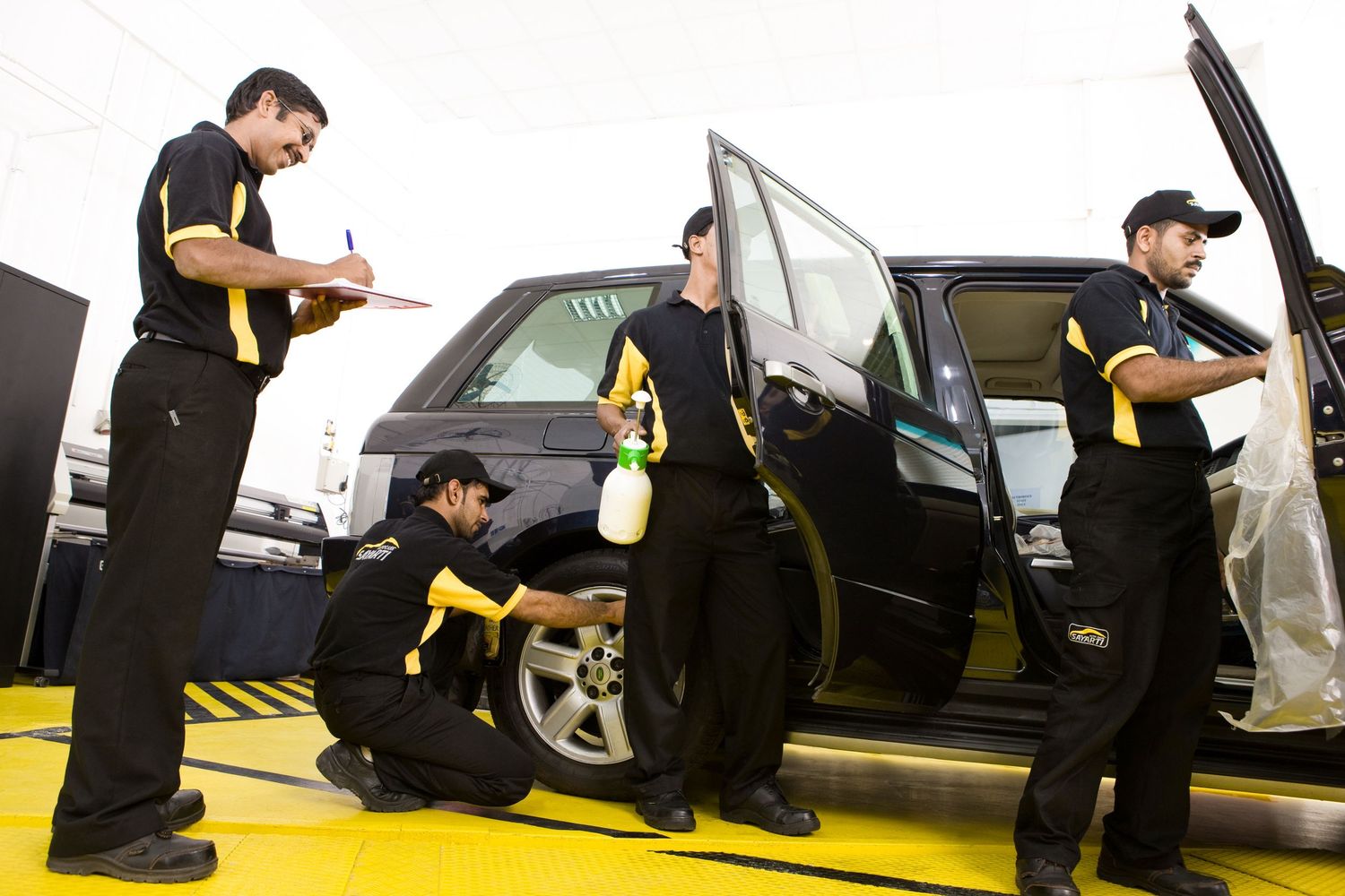 Automotive service team members working together in facility parking area.
