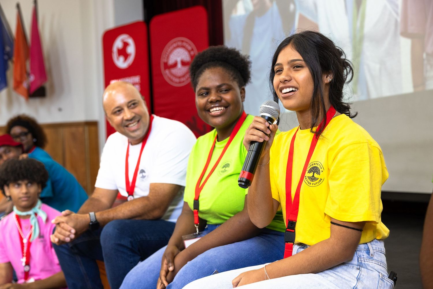 Diverse group of participants smile and interact during a colorful community event.