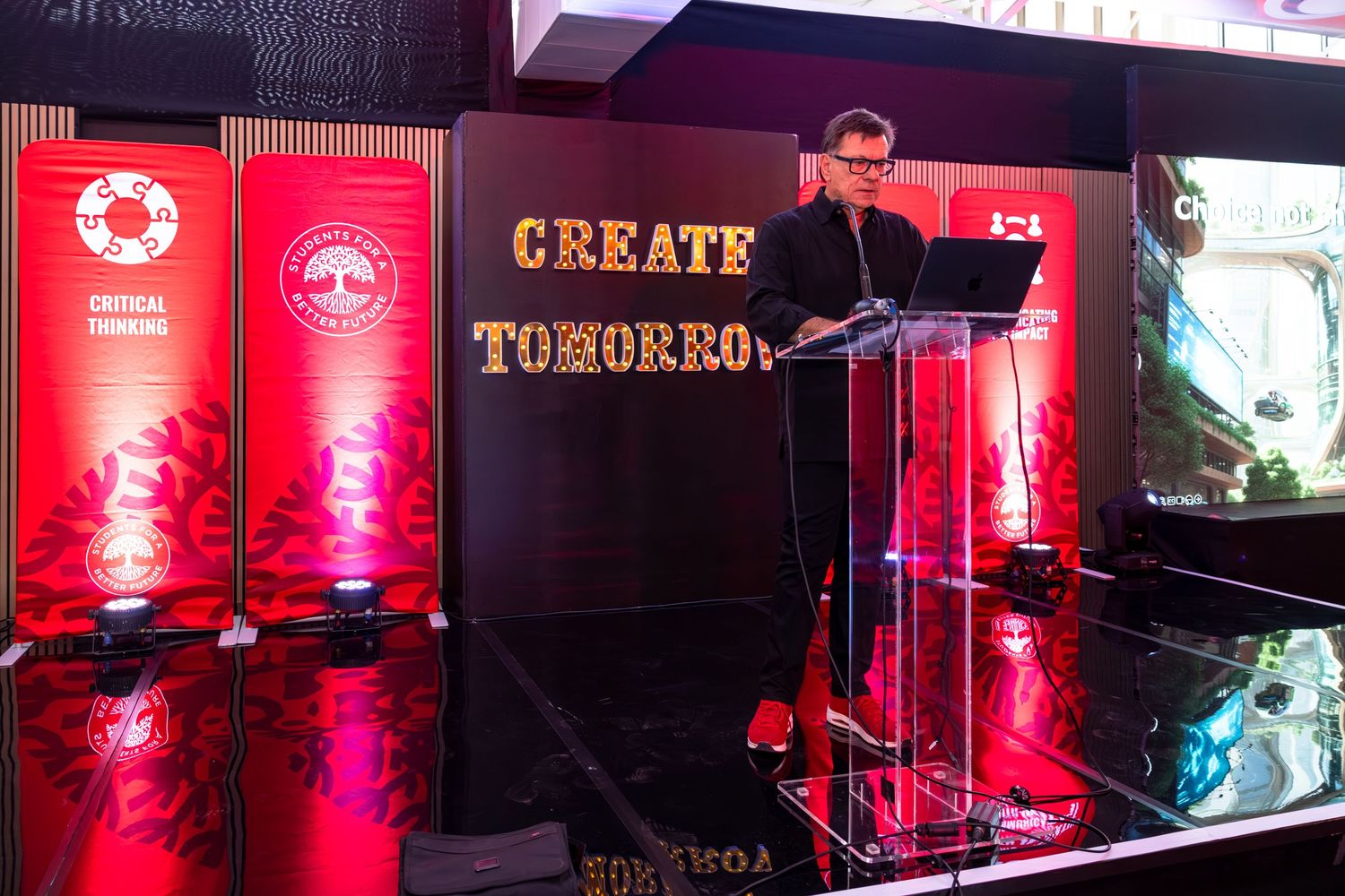 Event venue with red lighting and professional stage setup for conference presentation.