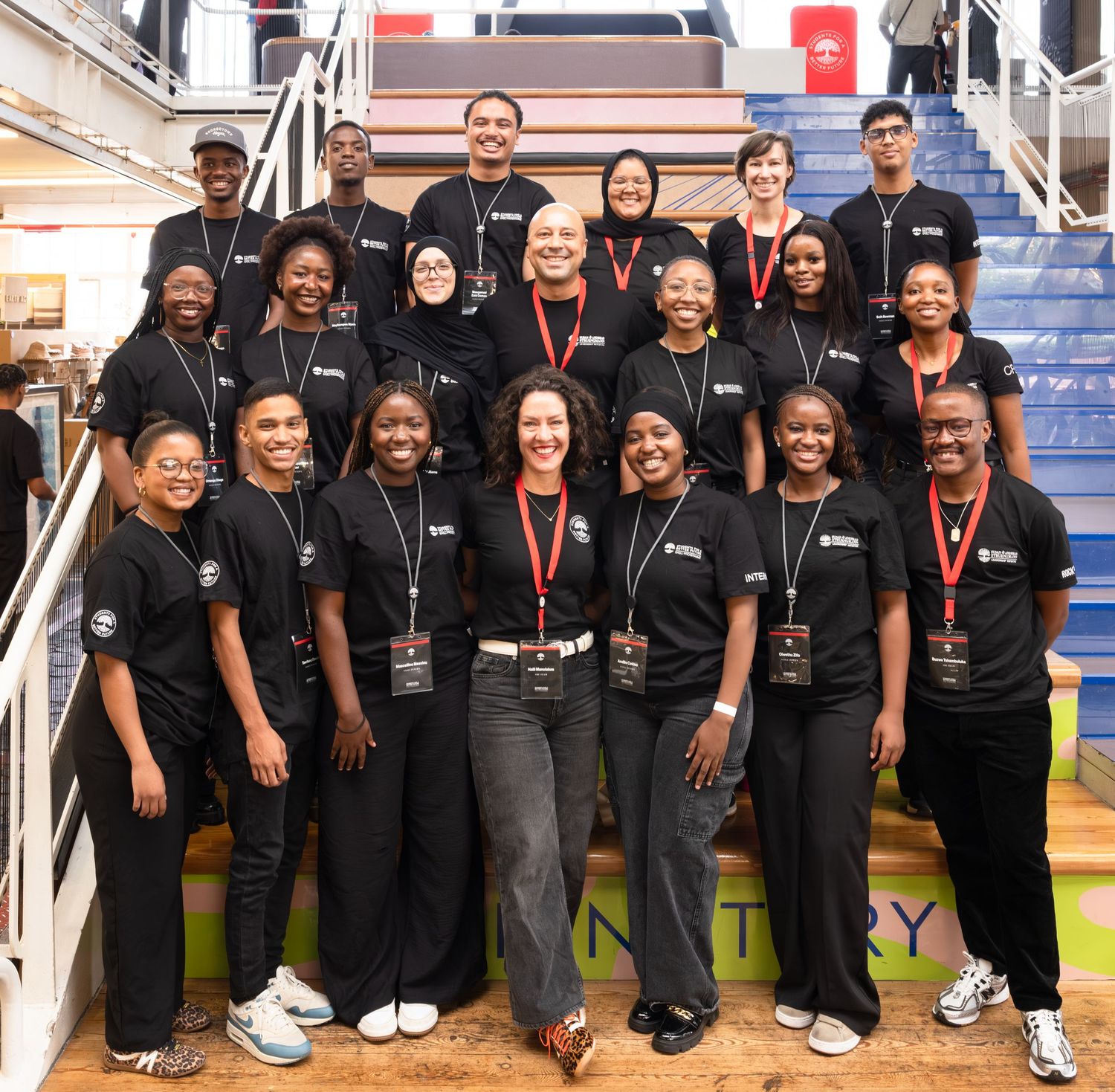 Group photo of diverse team members wearing matching black uniforms at a corporate event.