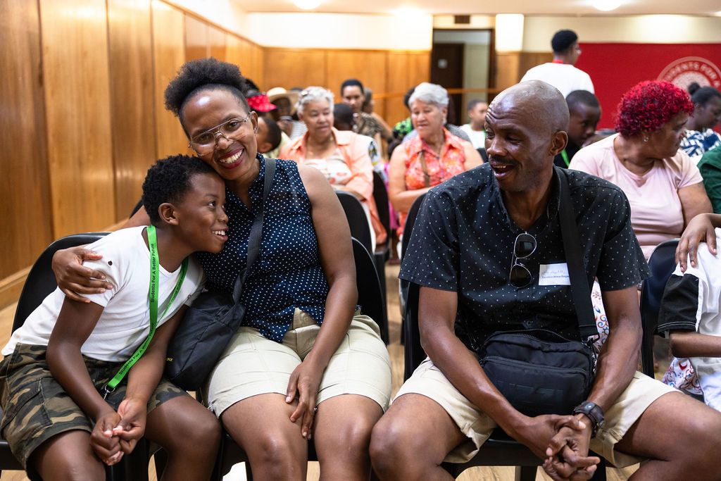 A group of people share a laugh while sitting together at a community gathering event.