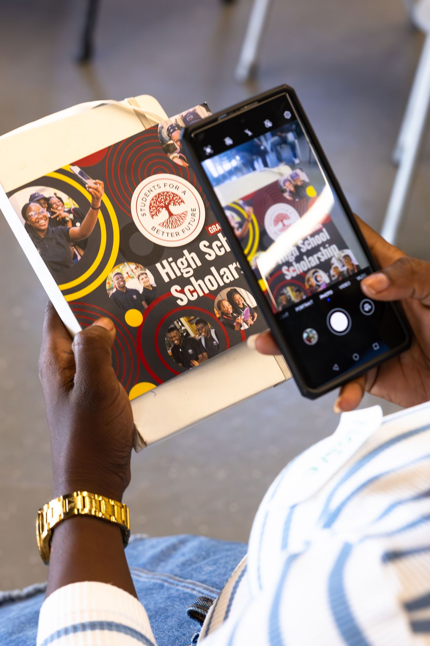 Person using mobile device to scan educational materials with program branding.
