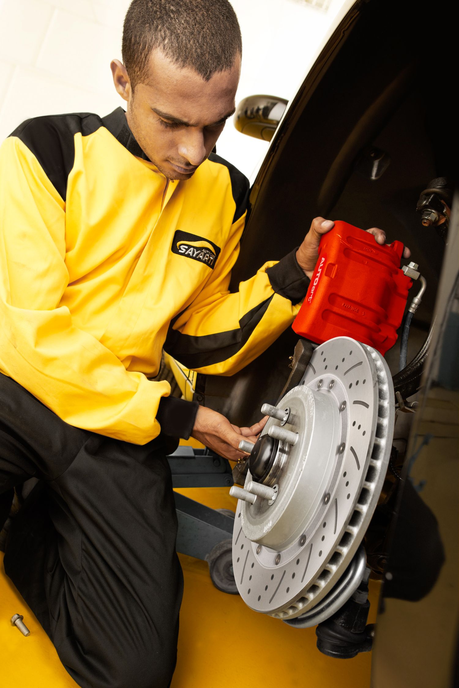 Technician examines brake rotor assembly during automotive service inspection.