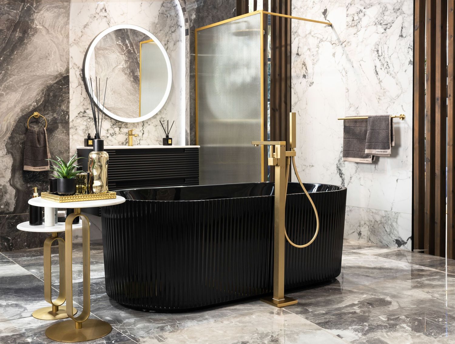 Luxurious marble bathroom with black freestanding tub and gold fixtures showcasing modern elegant design.