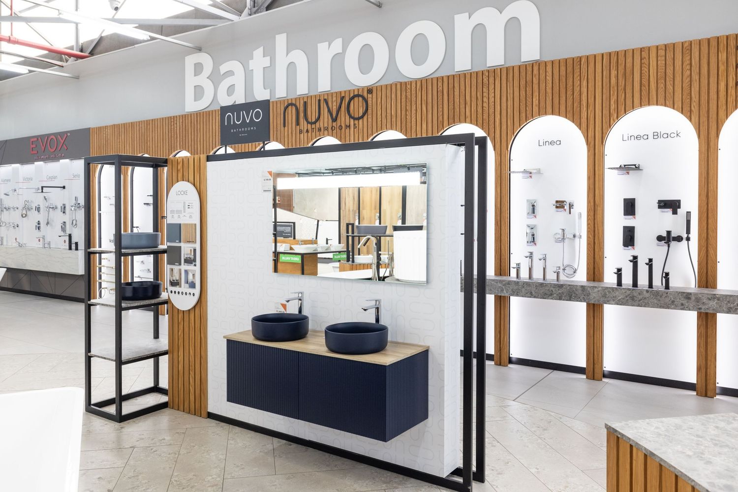 Retail display of bathroom fixtures and accessories with wooden slat wall panels and bright lighting.