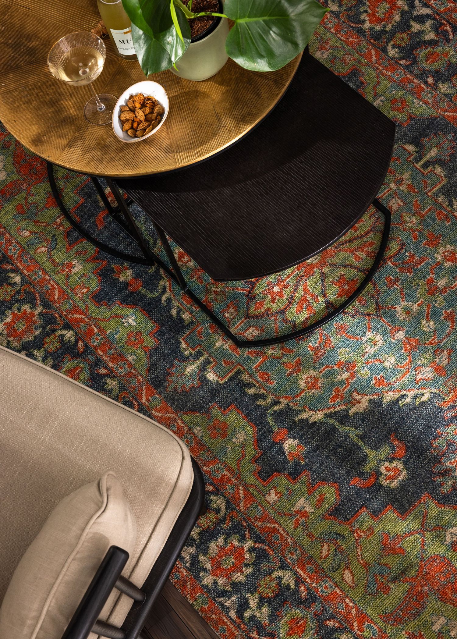 Vintage brass coffee table with snacks and plants on a richly patterned Persian area rug.