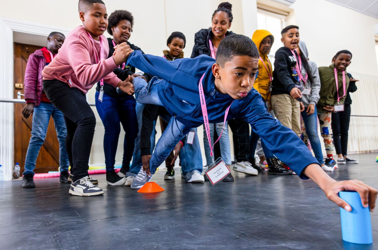 Group of students reaching down in synchronized movement during interactive game.