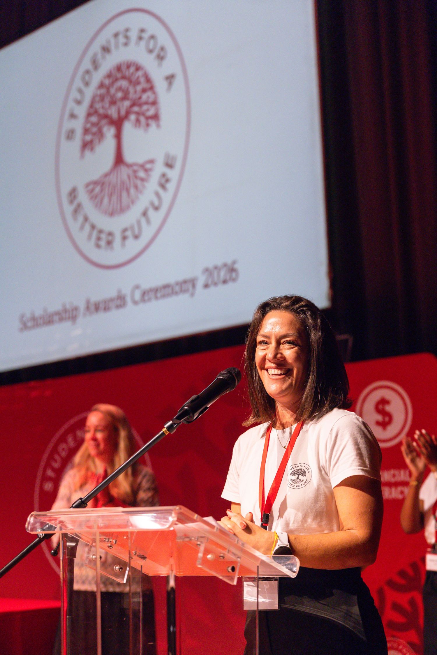 A speaker presents at a podium during a scholarship awards ceremony.