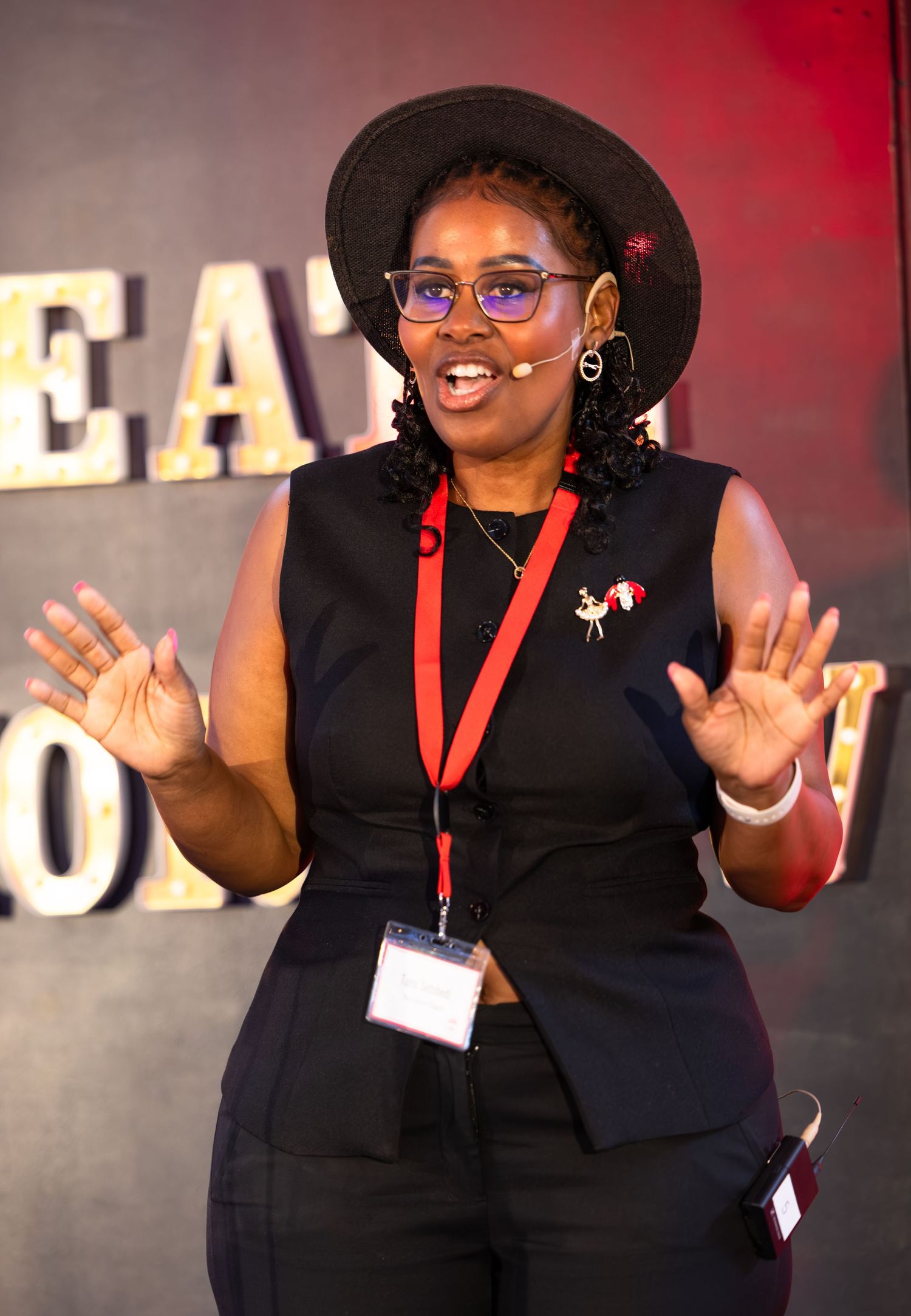 Speaker gestures enthusiastically while presenting on stage at a professional conference.