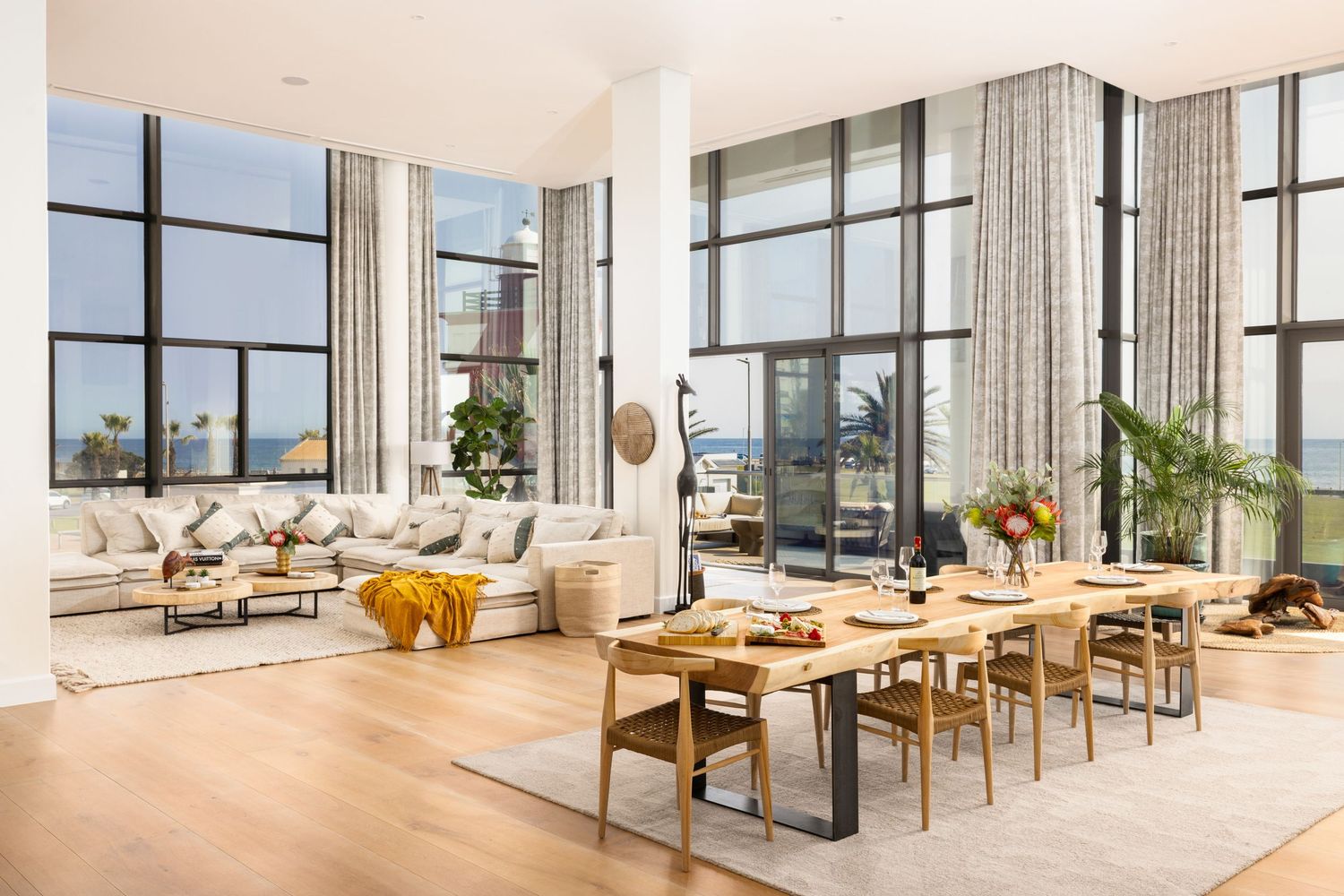 Spacious open-plan living and dining area with floor-to-ceiling windows and coastal views.