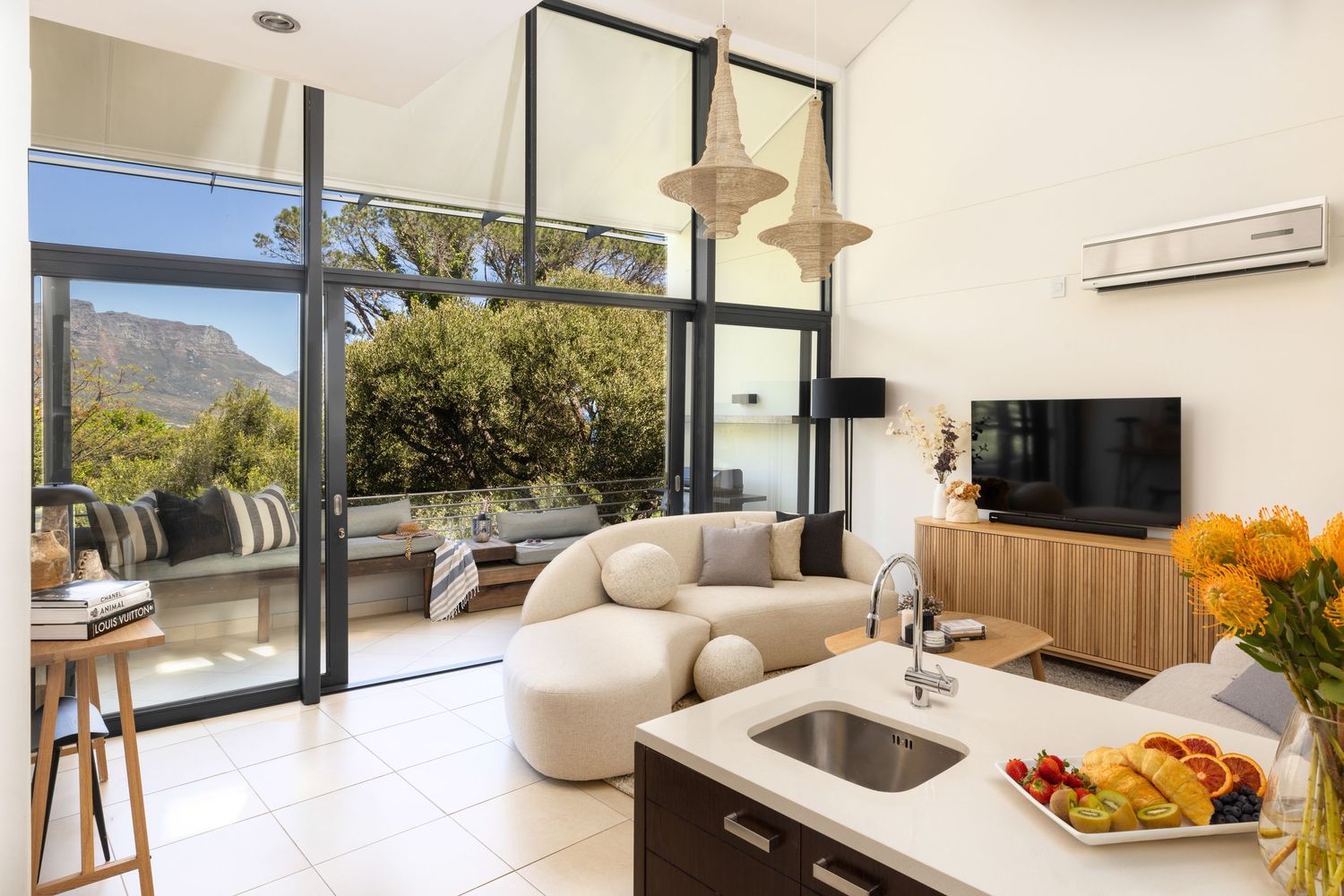 Contemporary open-concept living space with floor-to-ceiling windows, neutral furnishings, and mountain vistas.