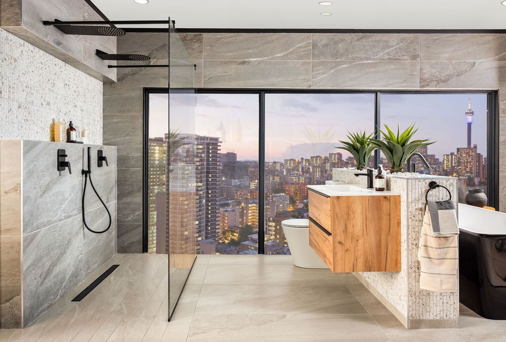 Modern bathroom interior with concrete walls, wooden elements, and panoramic city views through large windows.